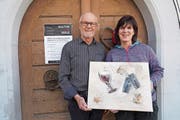 Der Winzer Paul Arnold (links) und die Künstler Evelyn Imhof-Winkler präsentieren vor dem Planzerhaus in Bürglen eines ihrer Werke. (Bild: Franz Imholz)