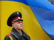 Ein ukrainischer Soldat steht Wache vor einer Landesfahne in Kiew. (Bild: KEYSTONE/EPA/SERGEY DOLZHENKO)