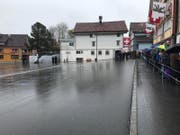Die Stimmberechtigten warten hinter der Absperrung. Unverzichtbar heute: der Regenschirm. (Bild: Luca Ghiselli)