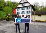 Vizepräsident Michael Schneider v/o Schruubä und Präsident Ralph Huber v/o Daffy präsentieren vor dem Pfadiheim Alte Mühle das neue Vereinslogo. (Bild: PD)