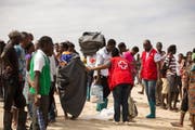 Mitarbeiter des Roten Kreuzes versorgen Menschen, die der tropische Wirbelsturm «Idai» in Moçambique obdachlos gemacht hat, mit Hilfsgütern. Bild: Denis Onyodi/EPA (21. März 2019)