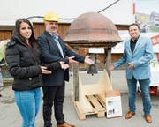 Tochter Dorine und Vater Marco Steiner von der Bauherrschaft überreichen dem Grabser Gemeindepräsidenten Niklaus Lippuner (rechts) stolz das historische Glöcklein samt Dachreiter. (Bild: Hansruedi Rohrer)