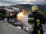 Ein Kleinflugzeug brennt, ein Feuerwehrmann greift ein: Notfallübung auf dem Flugplatz in Thun. (Bild: Keystone/ANTHONY ANEX)