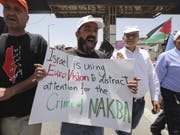 «Israel benutzt EuroVision, um vom Verbrechen der Nakba abzulenken» steht auf einem Plakat, mit dem Palästinenser an ihrem Tag der Katastrophe (Nakba) gegen den Eurovision Song Contest in Tel Aviv demonstrieren. (Bild: Keystone/AP/MAHMOUD ILLEAN)
