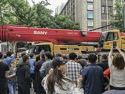 Schaulustige beobachten die Ankunft eines LKW-Hebekrans nach dem Einsturz eines Gebäudes in der Nähe. (Bild: Keystone/AP CHINATOPIX)