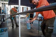 Zivilschützer füllen Flaschen für Anwohner ab, deren Trinkwasser verunreinigt wurde. (Bild: Samuel Golay/Ti-Press)