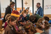 Kirchgänger stellen einen Anstecker her: Das kommt besonders bei den Kindern gut an. (Bild: Michel Canonica)
