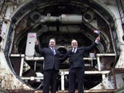 Die beiden Ingenieure Philippe Cozette (Franzose mit britischem Fähnlein) und Graham R. Fagg (Brite mit französischem Fähnlein) posieren zehn Jahre nach dem historischen Durchbruch vor der Eurotunnel-Bohrmaschine in Folkestone. (Bild: Hugo Philpott/Keystone, 1. Dezember 2000)