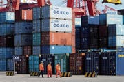 Arbeiter passieren gestapelte Container in einem Containerhafen in Qingdao in der ostchinesischen Provinz Shandong. (Bild: AP)