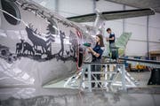 Die Lernende Chiara Christen (17) aus Alpnach föhnt Paul Wasers Scherenschnitte an das Demoflugzeug der Pilatus.(Bidld: Pius Amrein, Stans, 2. Mai 2019)
