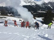 Einsatzkräfte schaufelten die brennende Fräse mit Schnee zu. (Bild: Kapo GR)