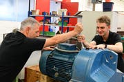 Ausbildner Kaspar Furrer und Lehrling Michael Glesti reparieren einen Motor samt Getriebe. /Bild: Werner Lenzin)