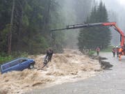 Spektakuläre Rettungsaktion in Splügen: Zwei Autoinsassen werden mit einem Kran aus dem reissenden Bach geborgen. (Bild: Kapo GR)