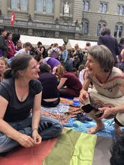 Iris Käser (rechts) im Gespräch mit einer Frau, die am Weltentuch näht.