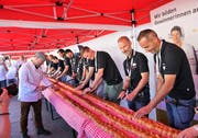 OK- Präsident Björn Britschgi (rechts) und das ganze OK schneiden zusammen mit Bäckermeister und Initiant Thomas Christen (links in weiss mit Messer) den Zopf an. (Bild: Romano Cuonz, 2.Mai 2019)