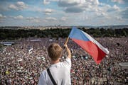 Ein Mann weht mit der tschechischen Flagge vor den hunderttausend Demonstranten, die sich am Sonntag in Prag versammelt haben. Bild: Martin Divisek/EPA (Prag, 23. Juni 2019)