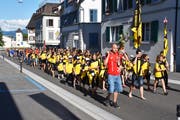 Hinter dem Hornträger und den Fahnenträgern laufen Verein und Dorfbewohner. (Bild: pd)
