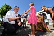 Schulpräsident Christoph Kohler nimmt von einer Kindergärtlerin einen Glückskäfer entgegen, damit der Neubau gut gelinge. (Bild: Manuel Nagel)