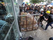 Mit einem Rollwagen aus Metall zertrümmert eine Gruppe von Demnonstranten eine Scheibe und stürmt das Parlament in Hongkong. (Bild: KEYSTONE/EPA/RITCHIE B. TONGO)