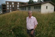 Der Horwer Gemeinderat Robert Odermatt (SVP) auf der Baurechtsparzelle, hinter ihm der leerstehende Kindergarten-Pavillon und eines der vier bestehenden Häuser der Überbauung Stirnrütipark. (Bild: Roman Hodel, Horw 8. Juli 2019)