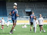 FCL-Goalgetter Blessing Eleke jongliert den Ball auf der Stirn, die Kids schauen bewundernd zu. Bild: Manuela Jans-Koch (Luzern, 14. Juli 2019)
