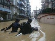Nepalesen waten mit ihrem Motorrad durch die überfluteten Strassen der Hauptstadt Kathmandu. (Bild: Keystone/AP/NIRANJAN SHRESTHA)
