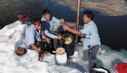 Othmar Monn, Bruno Leuzinger und Beat Walker (von links) machen Fondue auf dem kleinen Holzofen und stossen mit Weisswein an. (Bild: PD)