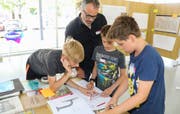 Architekt Felix Rutishauser rechnet mit drei jungen Teilnehmern Planmassstäbe um. (Bild: Christof Lampart)