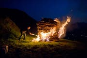 Ein Mann entzündet das Höhenfeuer in Urnäsch. (Bild: KEYSTONE/Ennio Leanza, 1. August 2011)