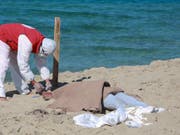 Ein libyscher Retter kümmert sich um eine der bisher 67 aus dem Mittelmeer geborgenen Leichen des Bootsunglücks vor der Hafenstadt Al-Chums. (Bild: KEYSTONE/AP/HAZEM AHMED)