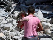 Ein Mann in Ariha, einem Ort in der syrischen Provinz Idlib, trägt ein Mädchen, das durch Luftangriffe verletzt wurde. (Bild: KEYSTONE/AP Syrian Civil Defense White Helme)