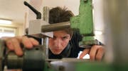 Ein Lehrling bei der Arbeit an der Maschine im Unterricht an der Abteilung Lehrwerkstätte für Möbelschreiner an der baugewerblichen Berufsschule Zürich. (Bild: Keystone)