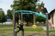 Stephanie Curjel (links) von der Jugend- und Gemeinwesenarbeit Cham und Gemein-derat Drin Alaj testen die neue Outdoor-Fitnessanlage. (Bild: PD)