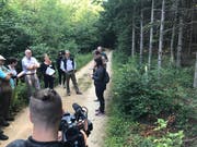 Projektleiterin Isabelle Glanzmann (oben, mit Unterlagen) erläutert vor Medien im Gelterkinder Wald den Nutzen der Ameisen und derer Inventarisierung. Rechts mit gelbem Pfosten markiert ist ein kleiner Ameisenhaufen unter einem Jungbaum. (Bild: Roger Lange Morf, Keystone-SDA)