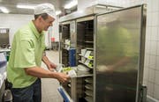 Ein Küchenmitarbeiter füllt einen der Regenerationswagen mit den bestückten Tabletts. Induktionsspulen erwärmen später das Essen. (Bild: Reto Martin)