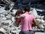 Durch Luftangriffe zerstört: In der Provinz Idlib sollen nun die Waffen schweigen. Ein Mann trägt in der Stadt Ariha ein verletztes Kind weg. (Bild: KEYSTONE/AP Syrian Civil Defense White Helme)