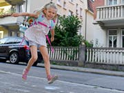 Sprung in eine neue Ära: Voller Freude hüpft diese Erstklässlerin dem ersten Schultag entgegen. (Bild: KEYSTONE/WALTER BIERI)