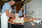 Vater Chrigel und Sohn Christian Forrer arbeiten beim Herausnehmen der Käsemasse Hand in Hand. (Bild: Adi Lippuner)