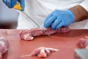Ein Metzger schneidet Fleisch (Bild: Keystone).