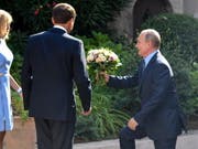 Blumen aus der Hand des russischen Präsidenten Wladimir Putin für die Frau des französischen Präsidenten, Brigitte Macron. (Bild: KEYSTONE/EPA AFP POOL/GERARD JULIEN / POOL)