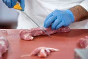 Ein Metzger schneidet Fleisch. (Bild: Keystone)