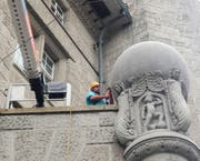 Ein Mitarbeiter einer Spezialfirma bei der Reinigung der Weltkugel über dem hinteren Eingang der Hauptpost am Bahnhofplatz. (Bild: Reto Voneschen -13. August 2019)
