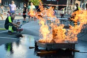 Unter Mithilfe und Anleitung des Feuerwehrmannes kann dieses Mädchen in Grabs den Brand erfolgreich löschen. (Bild: Hansruedi Rohrer)