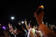 Mexikanische Bürger halten an der US-amerikanischen Grenze zum Gedenken an die Opfer von El Paso ihre leuchtenden Handys in die Luft. (Bild: Rey Jauregui/Keystone)