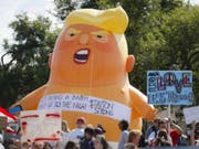 Demonstranten mit dem Baby-Trump-Ballon vor dem Spital, in dem einige der Opfer behandelt und das der US-Präsident besuchte. (Bild: Keystone/AP/JOHN MINCHILLO)