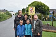 Melina und Dario hoffen zusammen mit ihren Eltern Patricia und Marco Vögel und Verkehrsvereins-Präsident Arnold Rossi (rechts), dass die Hinweistafeln «Freiwillig-Tempo 30» Autolenker zu rücksichtsvollem Verhalten auf der Wohnstrasse motivieren. (Bild: Thomas Schwizer)