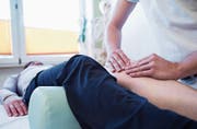 Ein Physiotherapeut behandelt in der Praxis das Knie einer Patientin. (Bild: Christin Klose/DPA)