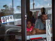Skeptische Blicke auf die Verwüstung: Ein Mann und ein Mädchen schauen aus einer Bäckerei in Freeport auf den Bahamas. (Bild: KEYSTONE/AP/RAMON ESPINOSA)