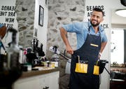 Arkan Nuri schnürt seine Barbier-Schürze in seinem Geschäft in der Zuger Altstadt. (Bild: Stefan Kaiser, Zug, 23. September 2019)