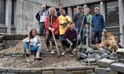 Eine Projektgruppe der Kanti Wattwil schafft neben dem Schulhauseingang Grünflächen für mehr Biodiversität. Selbst bei widrigen Bedingungen baut sie Steinmauern für Eidechsen, pickelt den Boden um und wühlt im Schlamm, um einen seichten Teich zu gestalten. Biolehrerin und Projektleiterin Gabriela Lutz (im gelben Mantel) ist stolz, mit wie viel Einsatz die Schüler bei der Arbeit sind.Bild: Timon Kobelt